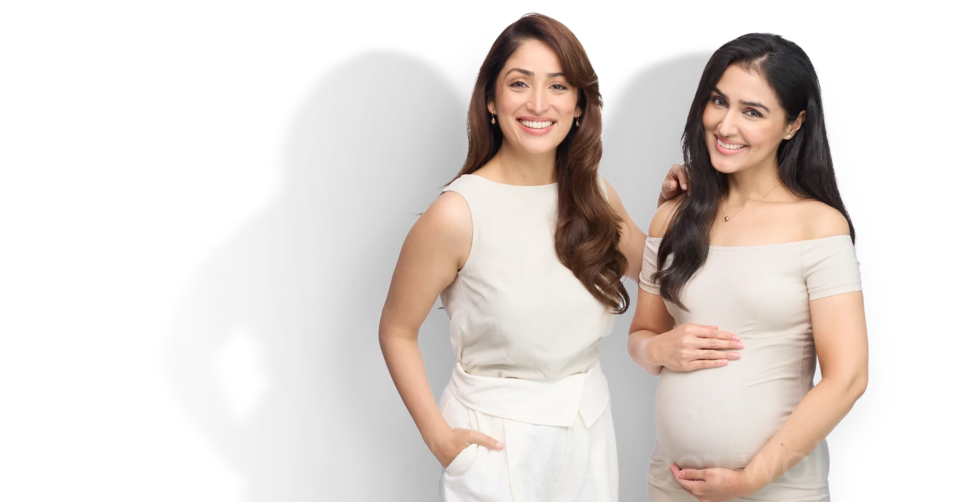Two smiling women in cream outfits, one of them pregnant